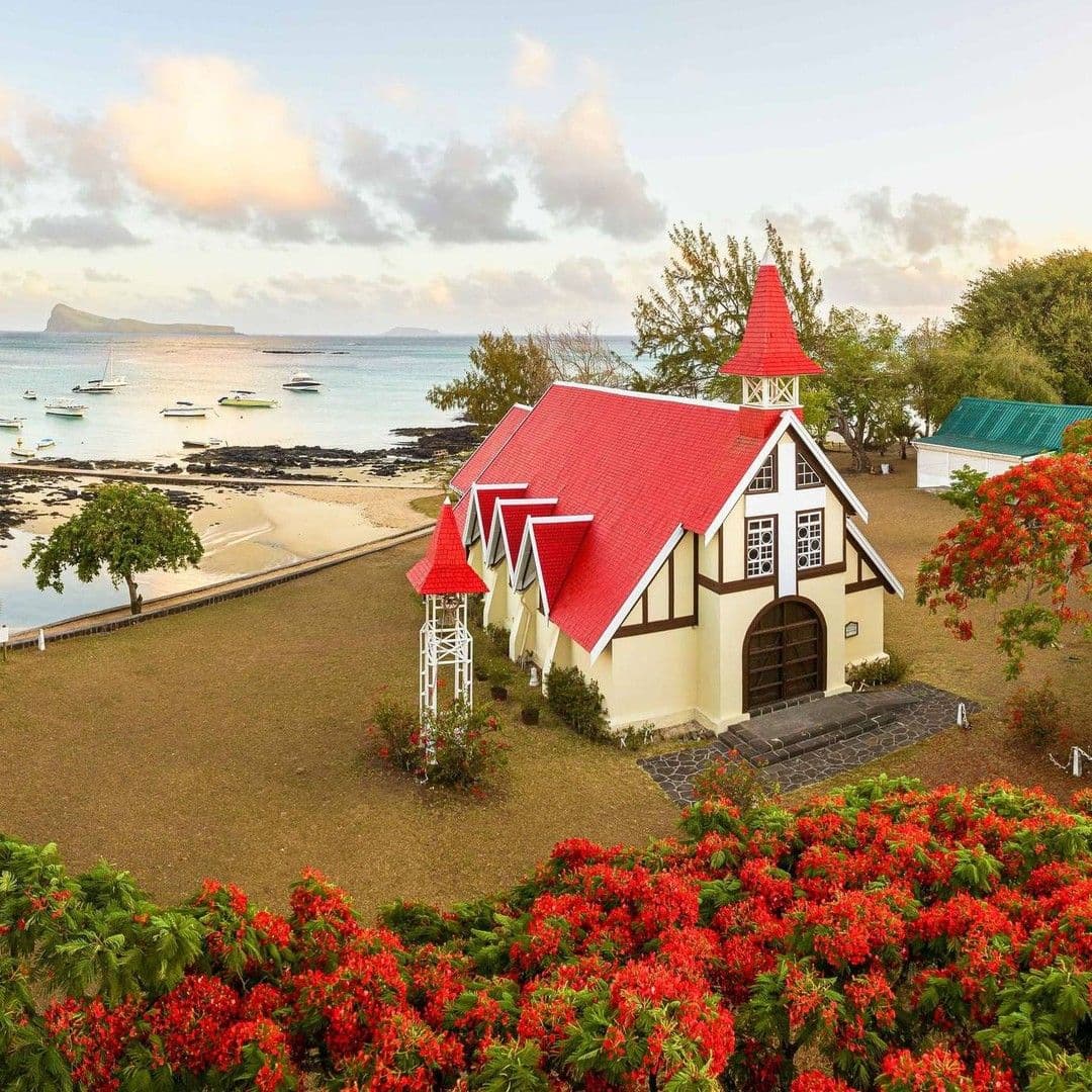Red-roofed seaside chapel surrounded by red flowers on the northern coast of Mauritius