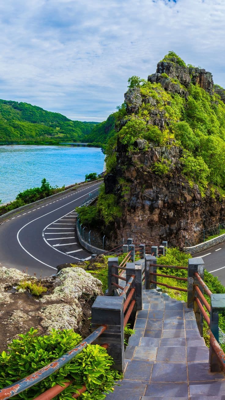 Coastal road curving around a green cliff above the sea at Macondé, southern Mauritius