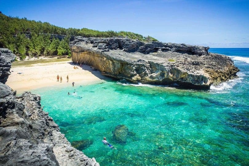 Turquoise cove and sandy beach framed by rocky limestone cliffs at Trou d’Argent, Rodrigues
