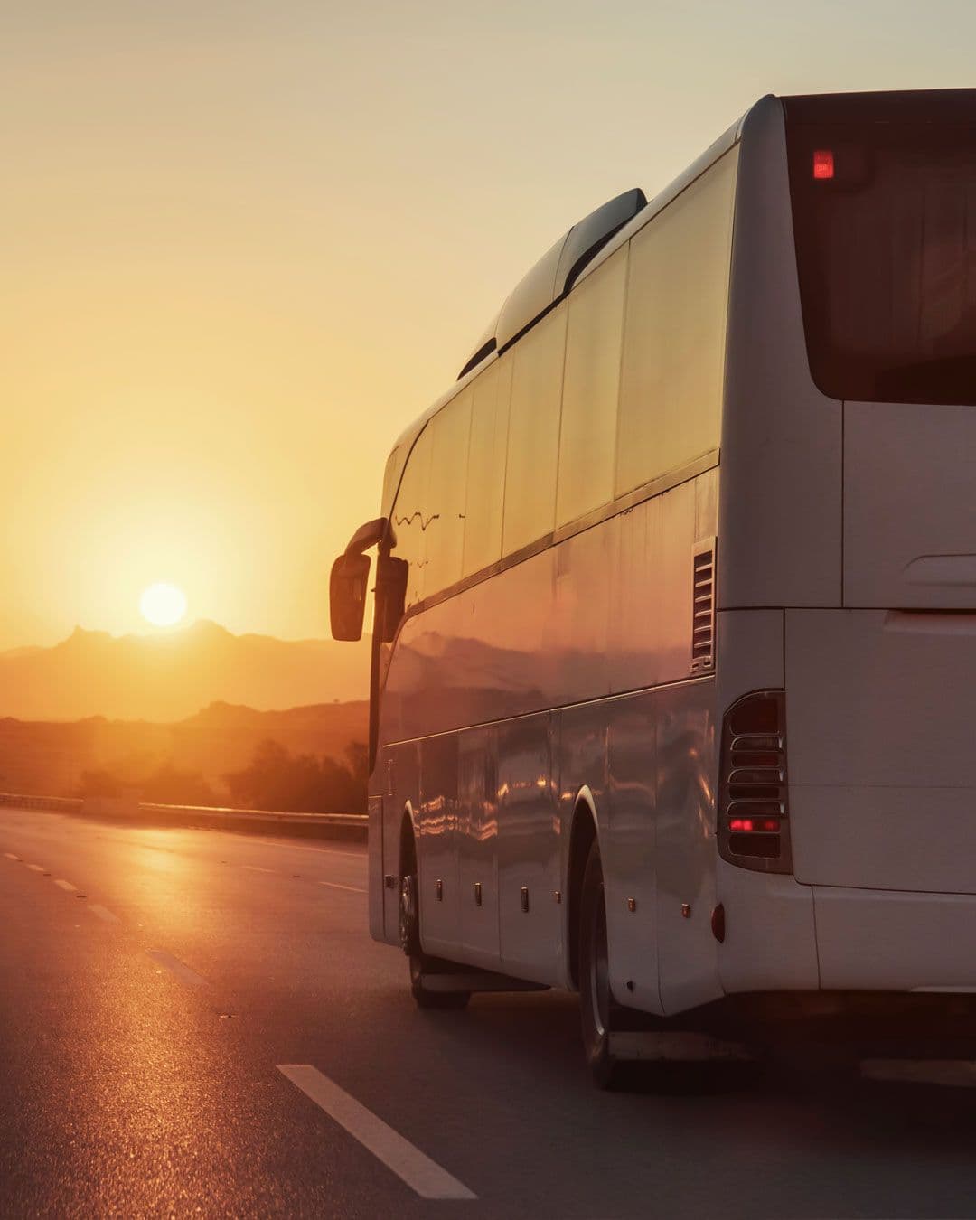 White coach driving along a road at sunset